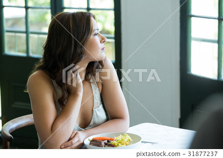 Thoughtful woman sitting at restaurant table 31877237
