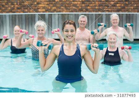 Trainer with senior swimmers exercising in swimming pool Trainer with senior swimmers exercising in swimming pool 31877493