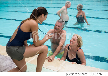 Trainer discussing timing with senior swimmers at poolside Trainer discussing timing with senior swimmers at poolside 31877669