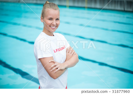 Happy female lifeguard standing at poolside Happy female lifeguard standing at poolside 31877960
