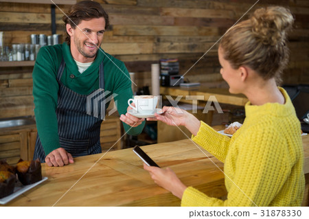 Barista serving coffee to female customer in cafeteria Barista serving coffee to female customer in cafeteria 31878330