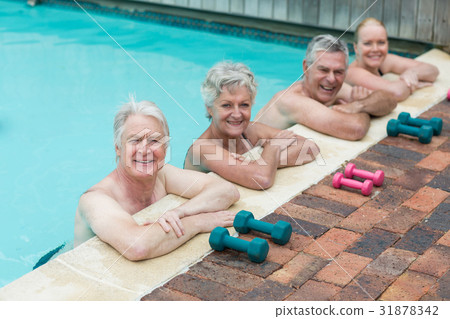 Swimmers leaning by dumbbells at poolside 31878342
