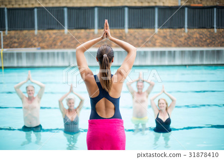 Yoga instructor assisting senior swimmers at poolside Yoga instructor assisting senior swimmers at poolside 31878410