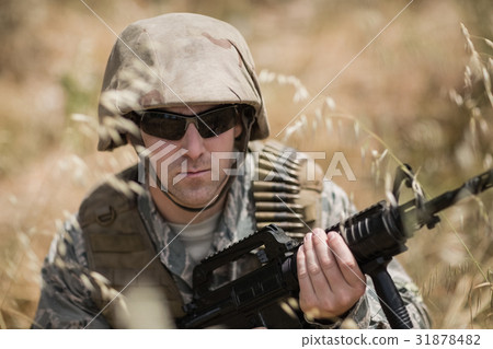 Military soldier hiding in grass while guarding with a rifle 31878482