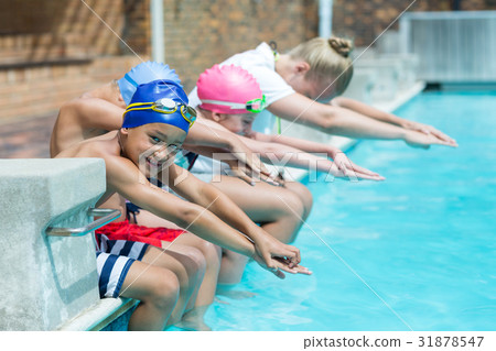 Swimming trainer teaching children at pool side Swimming trainer teaching children at pool side 31878547
