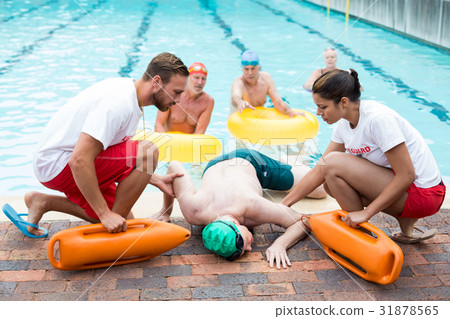 Male and female lifeguards helping unconscious man 31878565