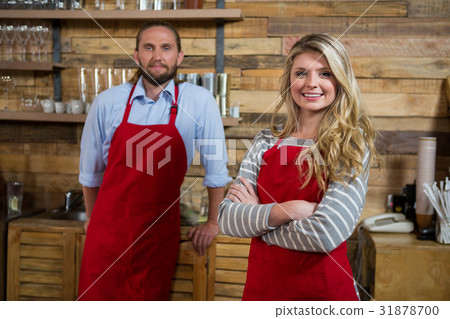 Smiling female barista with male colleague in coffee shop Smiling female barista with male colleague in coffee shop 31878700