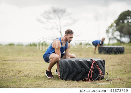 Fit woman flipping a tire during obstacle course Fit woman flipping a tire during obstacle course 31878759