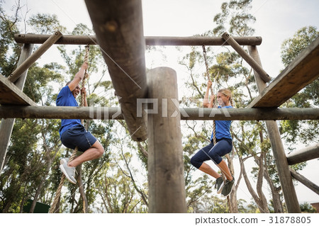 Fit man and woman climbing rope during obstacle course Fit man and woman climbing rope during obstacle course 31878805