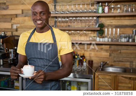Smiling male barista holding coffee cup in cafe 31878858