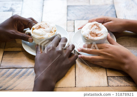 Multi ethnic couple hands holding coffee cups in cafe Multi ethnic couple hands holding coffee cups in cafe 31878921