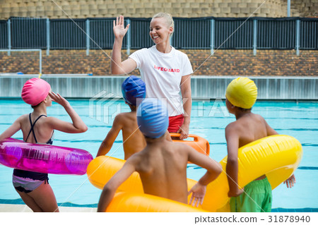 Lifeguard instructing children at poolside Lifeguard instructing children at poolside 31878940