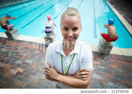 Confident female instructor standing at poolside Confident female instructor standing at poolside 31879046