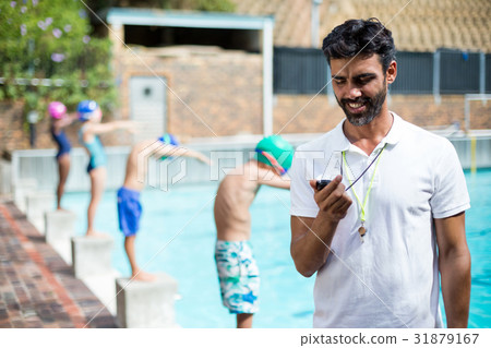 Instructor monitoring time while children standing on start blocks 31879167