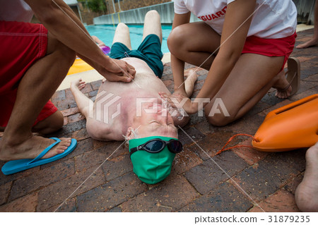 Lifeguards helping senior man at poolside 31879235