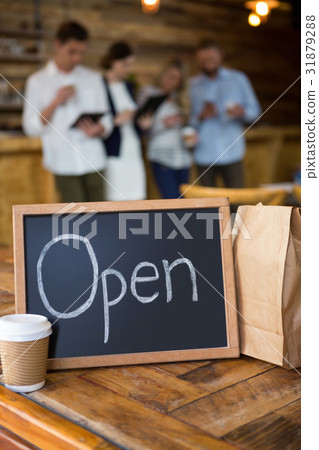 Open signboard with disposable coffee cup and paper bag in cafeteria Open signboard with disposable coffee cup and paper bag in cafeteria 31879288