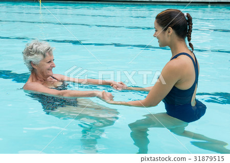 Female coach helping senior woman in swimming pool Female coach helping senior woman in swimming pool 31879515