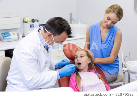 Dentist examining a young patient with tools 31879552