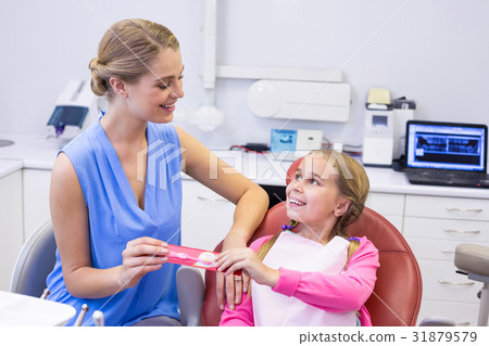 Mother giving tooth brush to daughter at dental clinic Mother giving tooth brush to daughter at dental clinic 31879579
