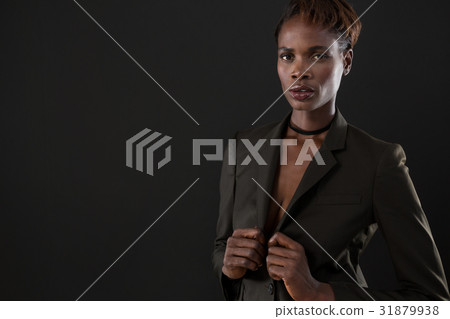 Androgynous man in suit posing against grey background 31879938