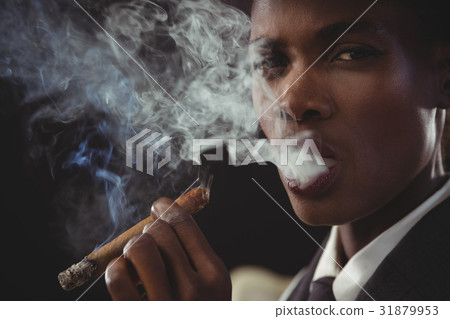 Androgynous man smoking cigar while sitting on a chair Androgynous man smoking cigar while sitting on a chair 31879953
