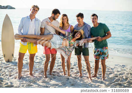 Friends holding young woman while standing on shore at beach 31880089