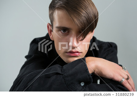Androgynous man in black shirt posing against grey background 31880239