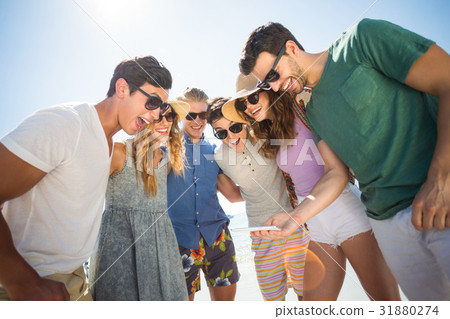 Happy young friends looking in mobile phone Happy young friends looking in mobile phone 31880274