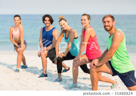Friends stretching on shore at beach Friends stretching on shore at beach 31880824
