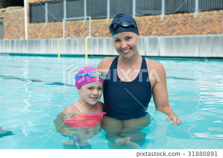 Portrait of female instructor and young girl standing in pool Portrait of female instructor and young girl standing in pool 31880891