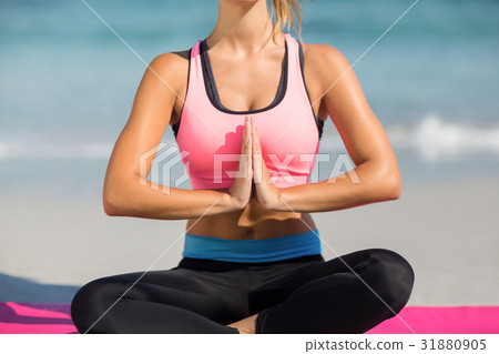 Woman meditating while sitting at beach 31880905