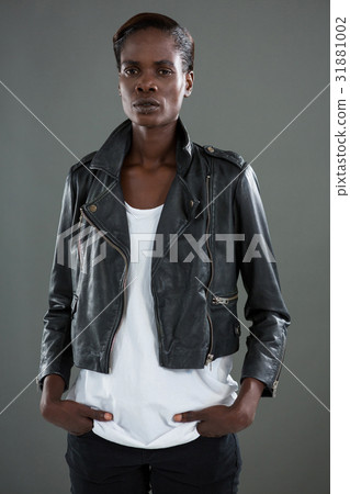 Androgynous man in black jacket posing against grey background 31881002