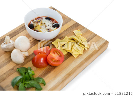 Cooked food in bowl by ravioli and vegetables on cutting board Cooked food in bowl by ravioli and vegetables on cutting board 31881215