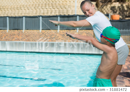 Female trainer training a boy for diving into pool Female trainer training a boy for diving into pool 31881472