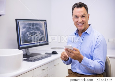 Portrait of happy dentist using mobile phone 31881526
