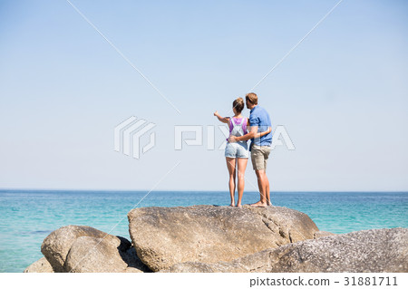 Couple standing on rock by sea 31881711