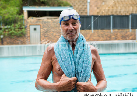 Senior man with towel over his shoulders standing at poolside 31881715