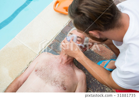 Lifeguard putting oxygen mask to senior man 31881735