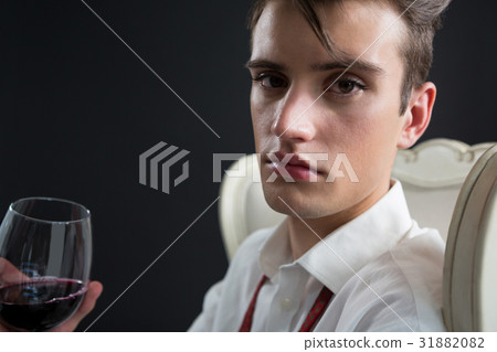 Androgynous man holding wine glass against black background 31882082