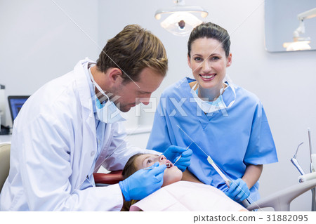 Dentists examining a young patient with tools Dentists examining a young patient with tools 31882095