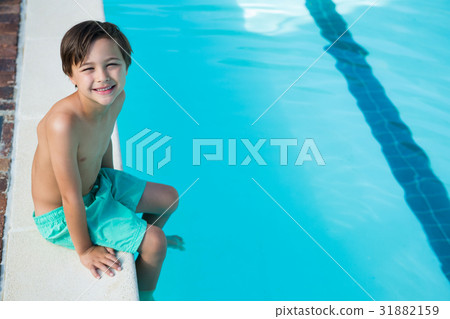 Smiling boy sitting at poolside Smiling boy sitting at poolside 31882159
