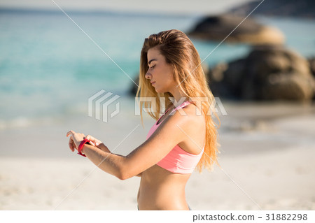 Woman looking at wristwatch while standing on shore 31882298