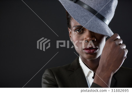 Androgynous man with hand on hat against grey background 31882695