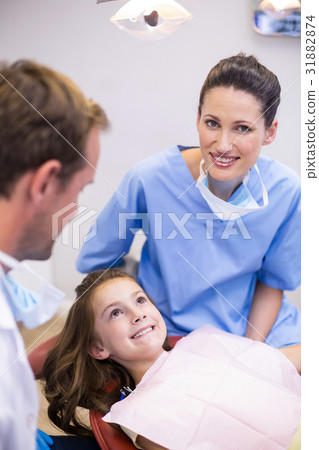 Smiling dentists interacting with young patient 31882874