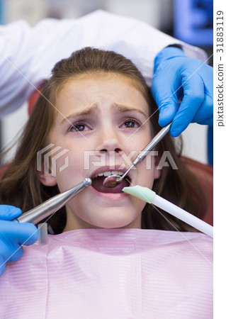 Dentists examining a young patient with tools 31883119