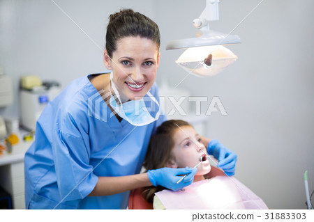 Dentist examining a young patient with tools in dental clinic Dentist examining a young patient with tools in dental clinic 31883303