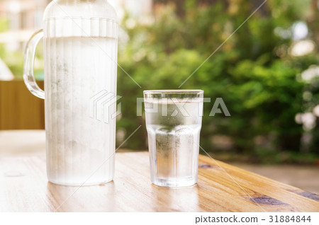 a glass of water on a wooden table. 31884844