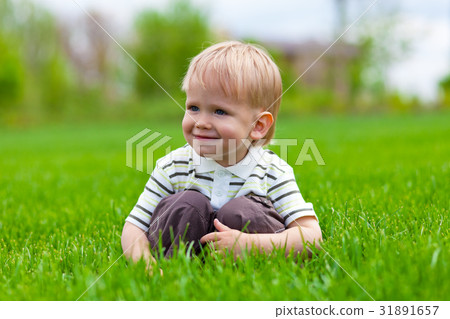 Smiling little boy sitting in fresh grass Smiling little boy sitting in fresh grass 31891657