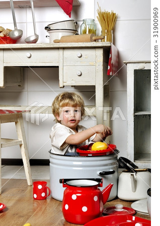 Adorable small child sits in kitchen inside a pan 31900969