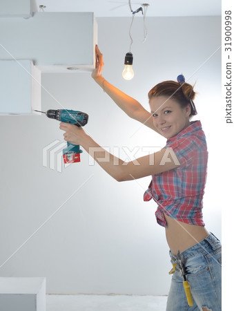 Beautiful young woman uses an electric drill 31900998